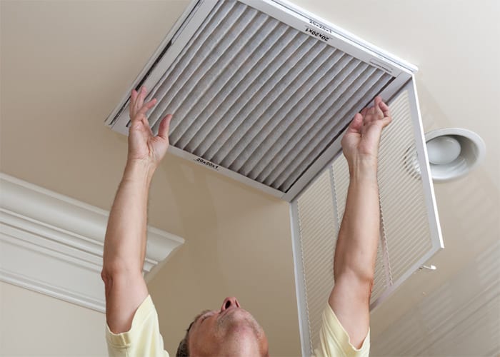 Man changing air conditioning filter in ceiling